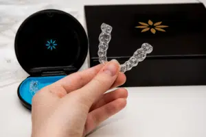 Hand holding clear aligners demonstrating how Invisalign attachments work during treatment